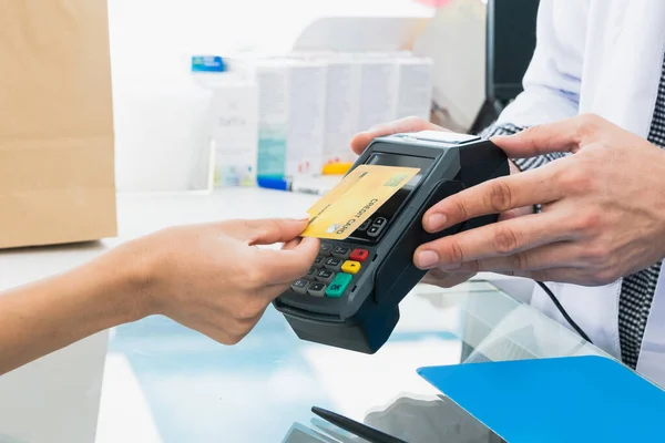 stock image Payment by credit card with payment terminal in qualified drugstore or hospital. Modern payment of electric money. Closeup customer purchase medication in pharmacy with credit card on pos.