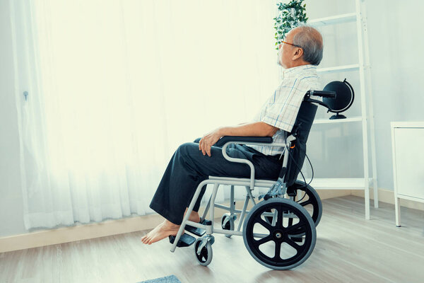 Portrait of an elderly man in a wheelchair alone with himself at home but contented with his lot in life. Convalescent facility for the crippled elderly in a nursing home.