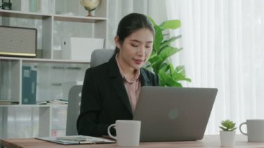 Ofiste çalışan ve dizüstü bilgisayar yazan hevesli bir iş kadını. Masasında oturmuş laptopla çalışan güzel bir ofis hanımı..