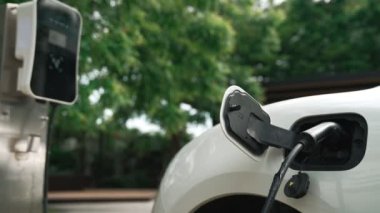 Yakın çekim yenilikçi modern ulaşım konsepti, elektrikli araba şarj istasyonunda gökyüzünden yansıyan yüksek detay ile şarj ediliyor. Yenilenebilir enerji tarafından kullanılan çevre dostu elektrikli araç.