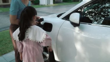 Evde şarj edilen elektrikli bir araçla okuldan yeni dönen anne ve kızın ilerici yaşam tarzı. Elektrikli araç, sürdürülebilir temiz enerjiyle çalışıyor..