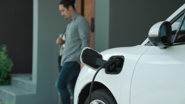 一个人在家里拔掉电动汽车充电器的插头 在进步的生活方式中使用电动汽车的概念有助于清洁和健康的环境 — 图库视频影像