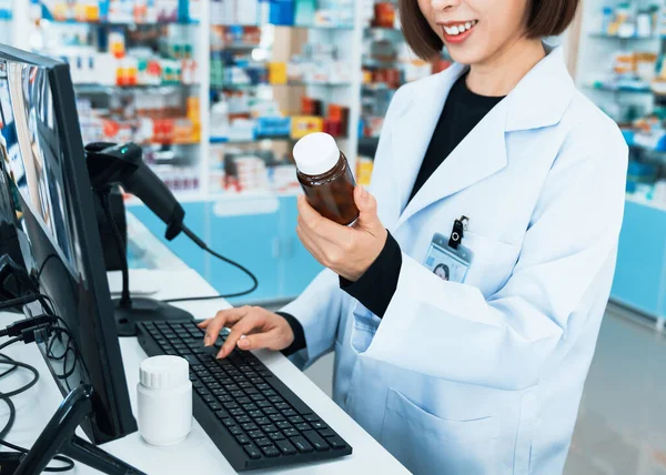 Closeup portrait of a young pharmacist and qualified pharmaceutical, medicine pill container or bottle mockup for copyspace at pharmacy. Drugstore concept with various medicine pills on