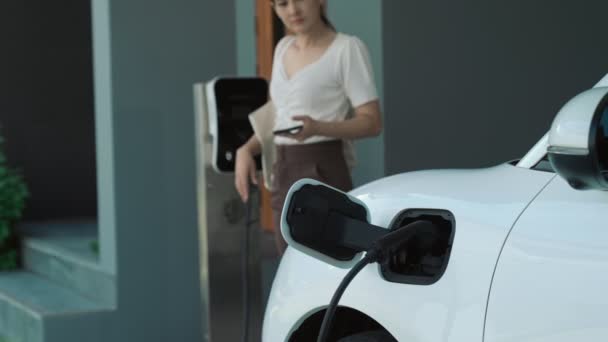 一个刚从家里充电的电动汽车上回来的现代妇女的进步生活方式 可持续清洁能源驱动的电动汽车 — 图库视频影像