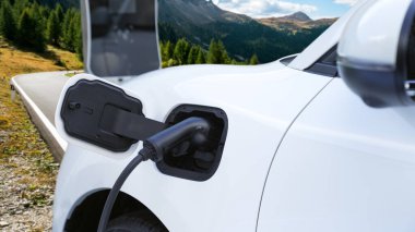 Tepe yolundaki şarj istasyonunda elektrikli arabanın çevresel farkındalığı için yenilikçi bir kavram. EV araba temiz çevre için yenilenebilir enerjiden güç alıyor.