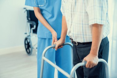 Physiotherapist assists contented senior man on folding walker. Recuperation for elderly, seniors care, nursing home.