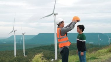 Oğluyla birlikte kırsal kesimdeki bir tepenin tepesinde ya da dağda bir rüzgar çiftliğinde mühendis. Yenilenebilir ve sürdürülebilir enerjinin gelecekteki üretimi için yenilikçi bir ideal. Rüzgar türbininden enerji üretimi.