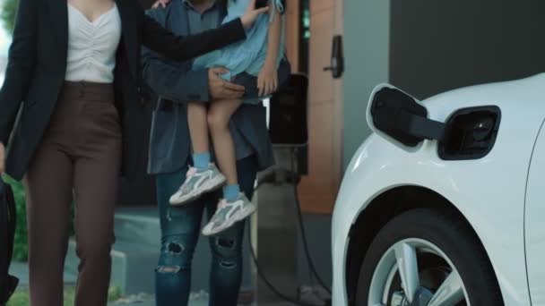年富力强的年轻父母和女儿住在有电动汽车和电动汽车充电站的家里 促进健康环境的电动汽车的绿色清洁能源 — 图库视频影像