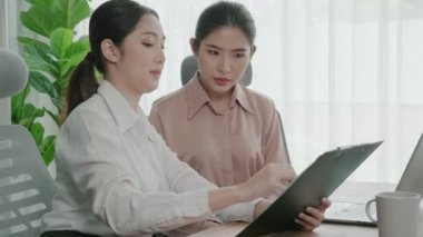 Ofis çalışma alanında birlikte çalışan iki genç hevesli iş kadını. Genç meslektaşlar tartışırken ve dizüstü bilgisayar kullanırken. Modern ofis çalışanları masada birlikte oturuyorlar..