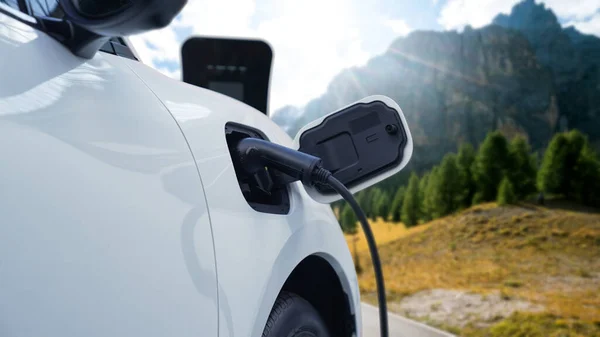 采用发电机驱动的可持续能源汽车动力 为具有山地背景的充电站充电蓄电池提供先进的旅行理念 大自然中的电动车是清洁环境的象征 — 图库照片