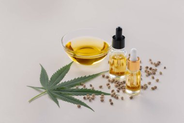 Şişede CBD yağı, damlacık kapağı, sativa yeşil kenevir ve kenevir tohumu bulunan yasallaştırılmış marihuana özellikleri. Copyspace ve reklam için esrar ürünü.