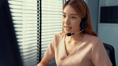 Competent female operator working on computer and while talking with clients. Concept relevant to both call centers and customer service offices.