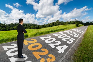 2023 yılbaşı yolculuğu ve gelecek vizyon konsepti. 2021 'in başında yeni ve başarılı bir başlangıç için mutlu bir yeni yıl kutlamasına giden otoyolda seyahat eden iş adamı. .