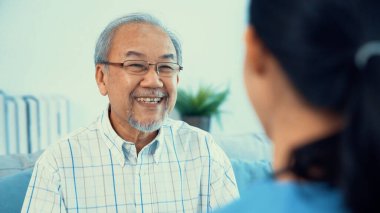 A young female doctor inquires about personal information of a contented senior at home. Medical care for the elderly, elderly illness, and nursing homes, home care.