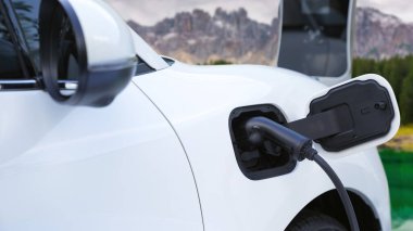 Elektro jeneratör sürücüsüyle enerji sürdürülebilir araba gücü, şarj istasyonunda şarj edilen batarya, ilerici seyahat konsepti için dağ zeminine sahip. Temiz ortamın sembolü olarak doğadaki EV otomobil.