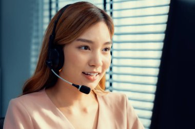 Competent female operator working on computer and while talking with clients. Concept relevant to both call centers and customer service offices.