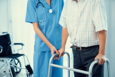 Physiotherapist assists her contented senior patient on folding walker. Recuperation for elderly, seniors care, nursing home.