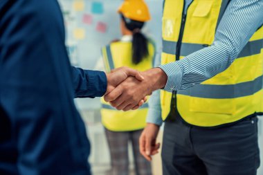 After concluding the meeting, competent investor shakes hands with engineer. Concept of the agreement between engineers and investors.