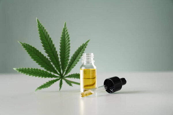 Лист конопли конопли конопли конопли с контейнером масла CBD с крышкой капельницы на белом фоне. Легализованная марихуана.
