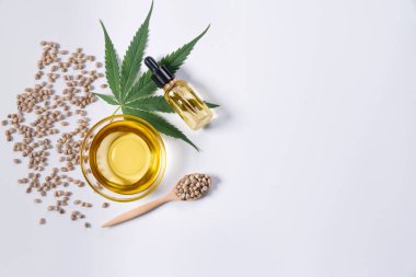 Şişede CBD yağı, damlacık kapağı, sativa yeşil kenevir ve kenevir tohumu bulunan yasallaştırılmış marihuana özellikleri. Copyspace ve reklam için esrar ürünü.