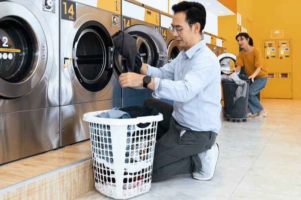 Asian people using qualified coin operated laundry machine in the public room to wash their cloths. Concept of a self service commercial laundry and drying machine in a public room.