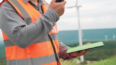 Kırsal kesimdeki bir tepenin tepesinde ya da dağda rüzgar çiftliğinde çalışan bir mühendis. Yenilenebilir ve sürdürülebilir enerjinin gelecekteki üretimi için yenilikçi bir ideal. Rüzgar türbininden enerji üretimi.