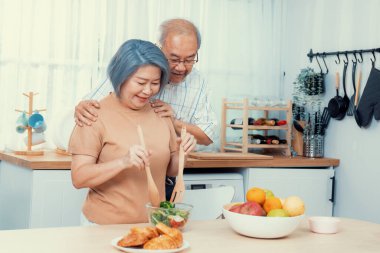 Contented senior couples who are happy to cook together with bread veggies and fruit in their kitchen.