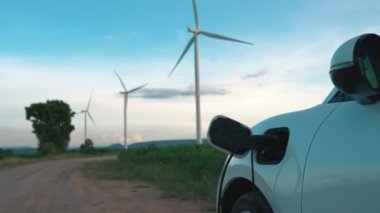 Çevreyi korumak için rüzgar türbininden yeşil ve yenilenebilir enerjiyle çalışan şarj istasyonunda şarj edilen gelişmiş gelecek enerji altyapısı konsepti.