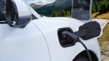 Tepe yolundaki şarj istasyonunda elektrikli arabanın çevresel farkındalığı için yenilikçi bir kavram. EV araba temiz çevre için yenilenebilir enerjiden güç alıyor.