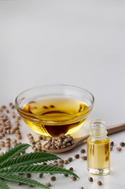 CBD yağı, cam kasede THC tintürü, damlalık kapaklı şişe ve boş arka planda kenevir yaprağı minimalizmle çevrili bir yığın kuru kenevir tohumu. Yasal marihuana konsepti.