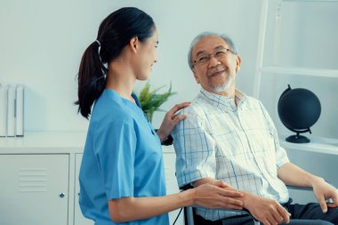 Happy positive asian nurse giving support and touching contented senior man with love. Nursing home for the elderly, elderly health and illness, senior patient carer.