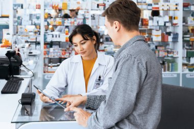 Kalifiye eczanedeki ödeme terminali ile kredi kartıyla ödeme. Elektrik parasının modern finansal ödemesi. Eczaneden eczacının reçetesiyle beyaz müşteriler ilaç satın alıyor..