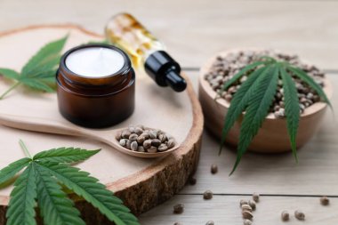 Kenevir ve kozmetik konseptinde CBD yağ şişeleri, krema kavanozu ve kenevir tohumları bulunur. Cilt ürünleri için yasallaştırılmış esrar.