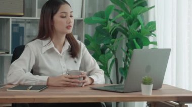 Ofiste çalışan ve dizüstü bilgisayar yazan hevesli bir iş kadını. Masasında oturmuş laptopla çalışan güzel bir ofis hanımı..