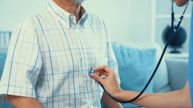 Caring young female doctor performing osteopathy treatment for a contented senior patient. At-home medical treatment for an Asian senior patient, joint pain treatment, medical service for seniors.