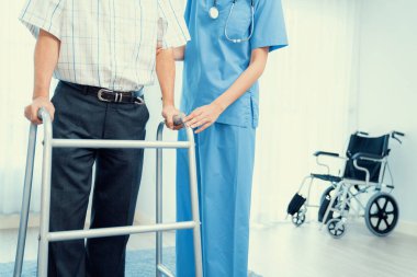 Physiotherapist assists her contented senior patient on folding walker. Recuperation for elderly, seniors care, nursing home.