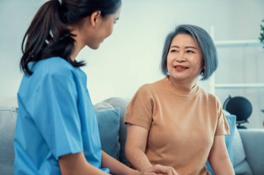 A contented senior woman visited by her personal caregiver and hold each others hands.