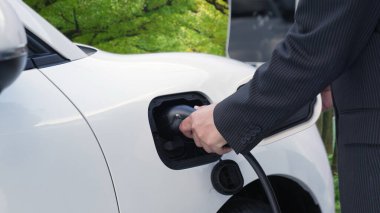 Çevre bilincini artırmak için sürdürülen ilerici kampanya, yeşil ormandaki şarj istasyonundan elektrik enerjisiyle çalışan elektrikli aracını şarj ediyor. Gelecekteki otomobiller için EV otomobil.