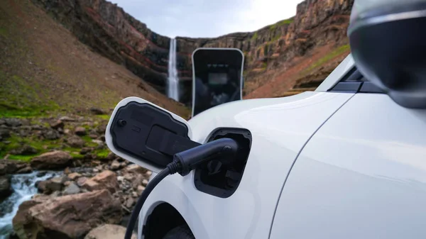 自然景観 滝やストリームの背景に充電ステーションから電気自動車の充電エネルギー 再生可能エネルギーを動力とするEv車によるエネルギー持続可能性の進歩的な概念 — ストック写真