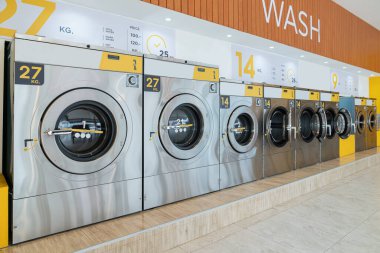Halka açık bir mağazada kaliteli para ile çalışan bir dizi çamaşır makinesi. Kamu dairesinde ticari çamaşır ve kurutma makinesi kavramı.