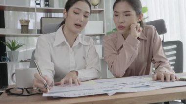 Ofis çalışma alanında birlikte çalışan iki genç hevesli iş kadını. Genç meslektaşlar tartışırken ve dizüstü bilgisayar kullanırken. Modern ofis çalışanları masada birlikte oturuyorlar..