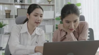 Ofis çalışma alanında birlikte çalışan iki genç hevesli iş kadını. Genç meslektaşlar tartışırken ve dizüstü bilgisayar kullanırken. Modern ofis çalışanları masada birlikte oturuyorlar..