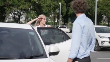 İlerici iş adamı ve iş kadını şehir merkezinde dolaşmadan önce şarj istasyonuna bağlı elektrikli arabaya yaslanıyor. Çevre dostu şarj edilebilir araba temiz enerjiyle çalışıyor..