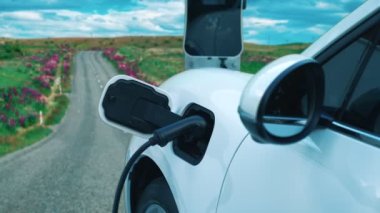 Tepe yolundaki şarj istasyonunda elektrikli arabanın çevresel farkındalığı için yenilikçi bir kavram. EV araba temiz çevre için yenilenebilir enerjiden güç alıyor.
