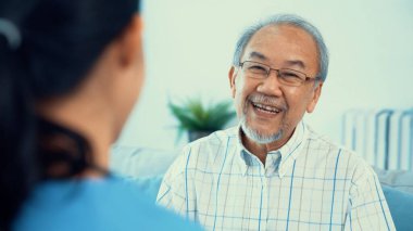 A young female doctor inquires about personal information of a contented senior at home. Medical care for the elderly, elderly illness, and nursing homes, home care.
