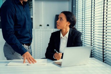 Competent female employee discussing with her colleague, employer using laptop at her office. Interpersonal relations among coworkers.