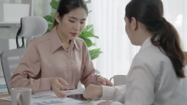 Ofis çalışma alanında birlikte çalışan iki genç hevesli iş kadını. Genç meslektaşlar tartışırken ve dizüstü bilgisayar kullanırken. Modern ofis çalışanları masada birlikte oturuyorlar..