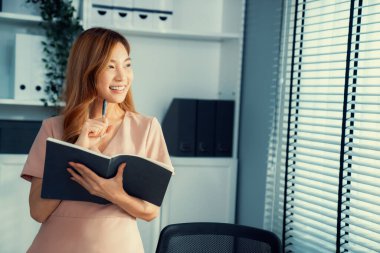 Young competent office lady, intern, secretary holding a log in office room. Concept of various career for office working. Concept of diverse office careers.