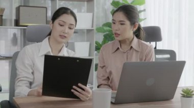 Ofis çalışma alanında birlikte çalışan iki genç hevesli iş kadını. Genç meslektaşlar tartışırken ve dizüstü bilgisayar kullanırken. Modern ofis çalışanları masada birlikte oturuyorlar..