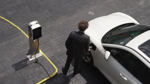 진취적 사업가 도심에서 자동차를 다니기 주유소에서 자동차로 충전기 플러그를 뽑는다 — 비디오
